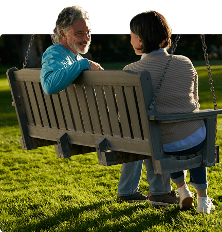 Man and woman sitting on park bench swing.