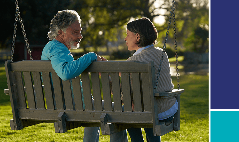 Man and woman sitting on park bench swing.