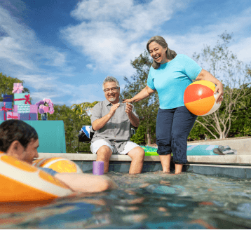 Two men and women sitting next to the pool.