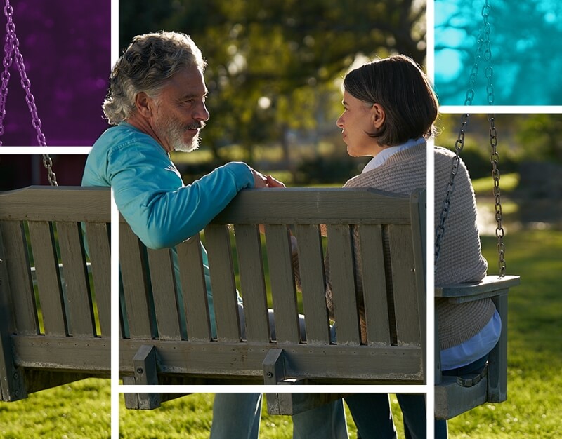 Man and woman sitting on park bench swing.