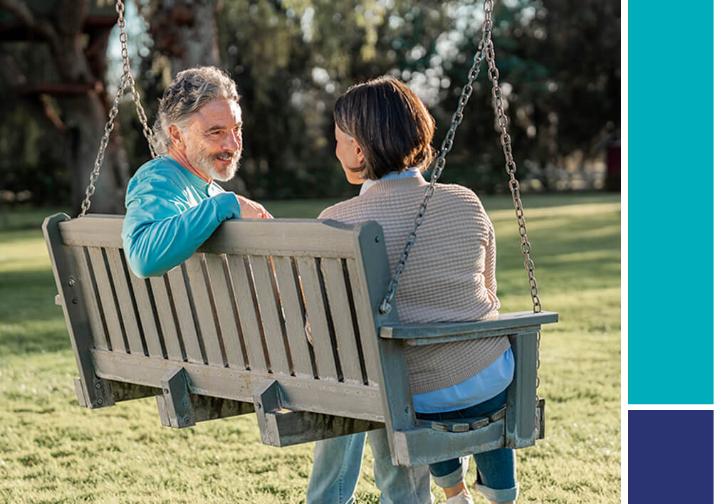 Man and woman sitting on park bench swing.