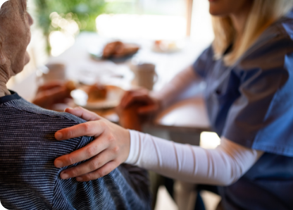 A woman placing her hand on a patient's  shoulder.